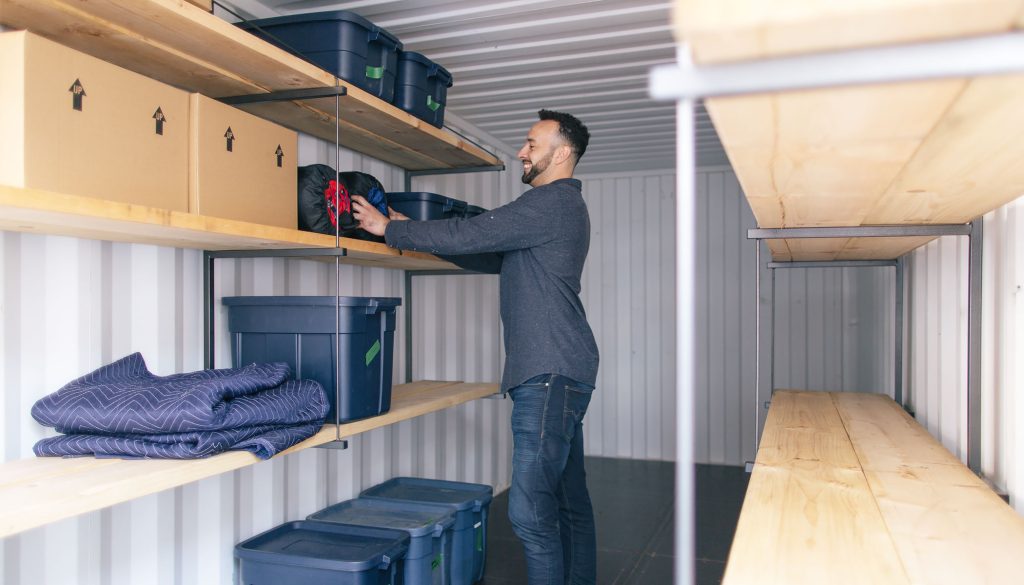 man storing boxes in storage container